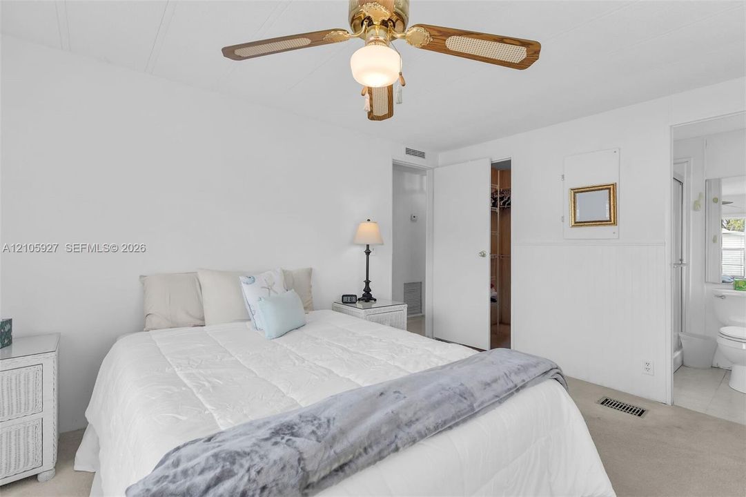 Room featuring a neutral wall finish, a ceiling fan with integrated lighting, and a doorway leading to a walk-in closet
