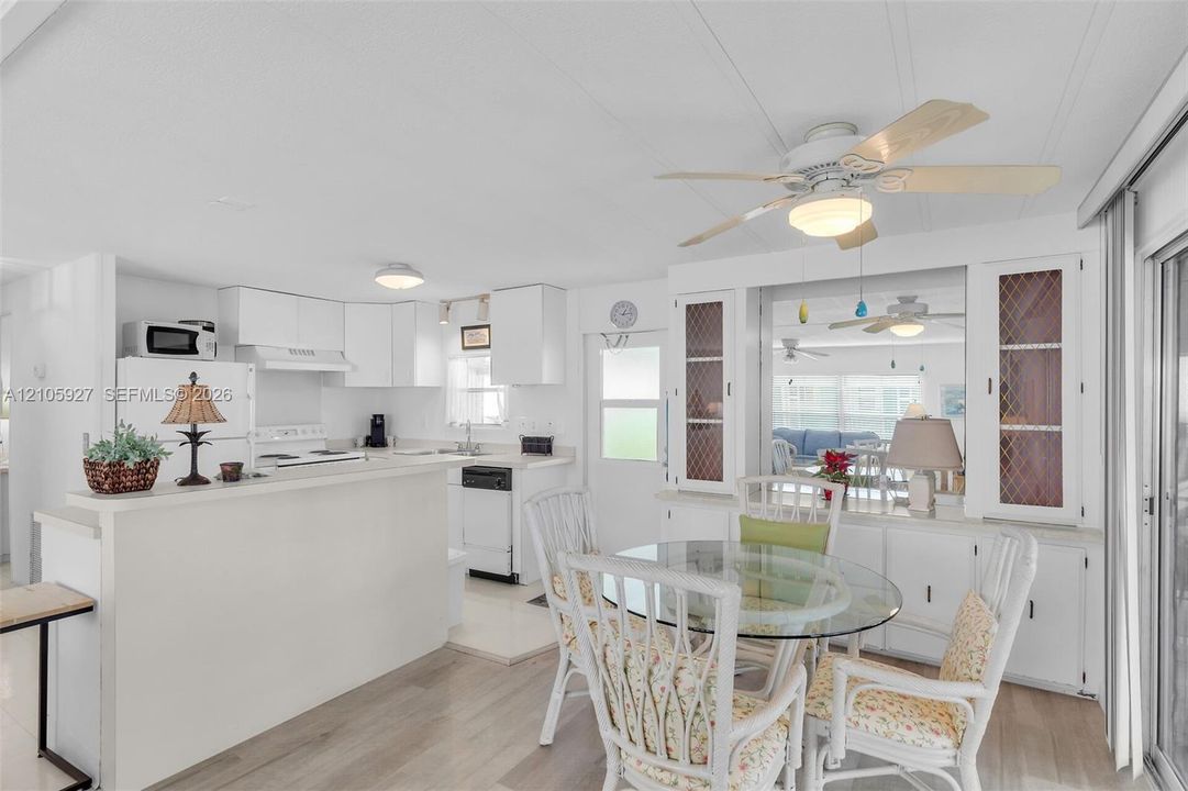 Kitchen featuring a breakfast bar, white cabinetry, integrated appliances, wood-finish flooring, and built-in glass-paneled display hutches