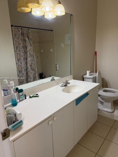 Bathroom vanity featuring a solid-surface countertop with an integrated basin, white cabinetry, a large wall-mounted mirror, and multi-bulb decorative light fixture