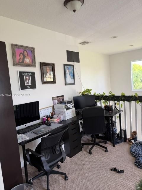 Textured carpeting, neutral wall color, and white baluster railing with a dark handrail
