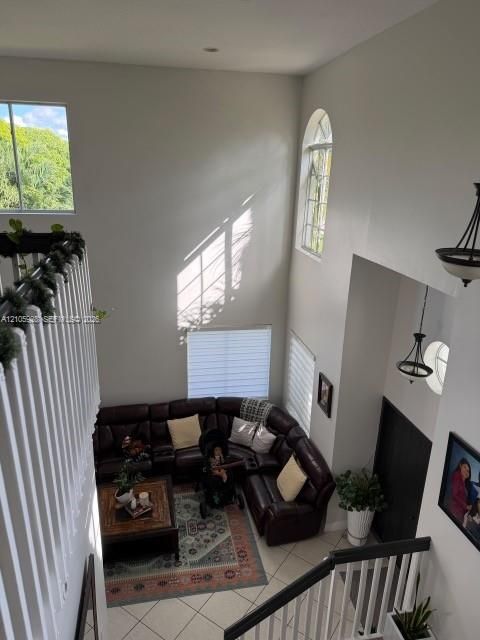 Double-height ceiling, multi-level windows, arched window detail, tile flooring, and tiered pendant lighting