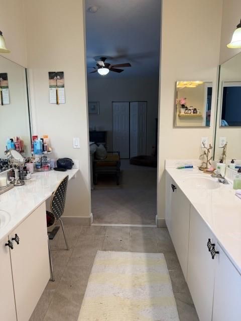 Dual vanities featuring white cabinetry, light-toned countertops, oversized wall-mounted mirrors, and decorative hardware