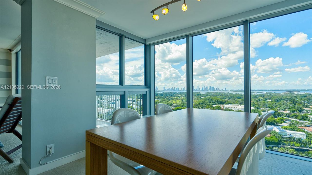 Floor-to-ceiling windows featuring panoramic city and water vistas, crown molding, and a modern multi-bulb linear light fixture