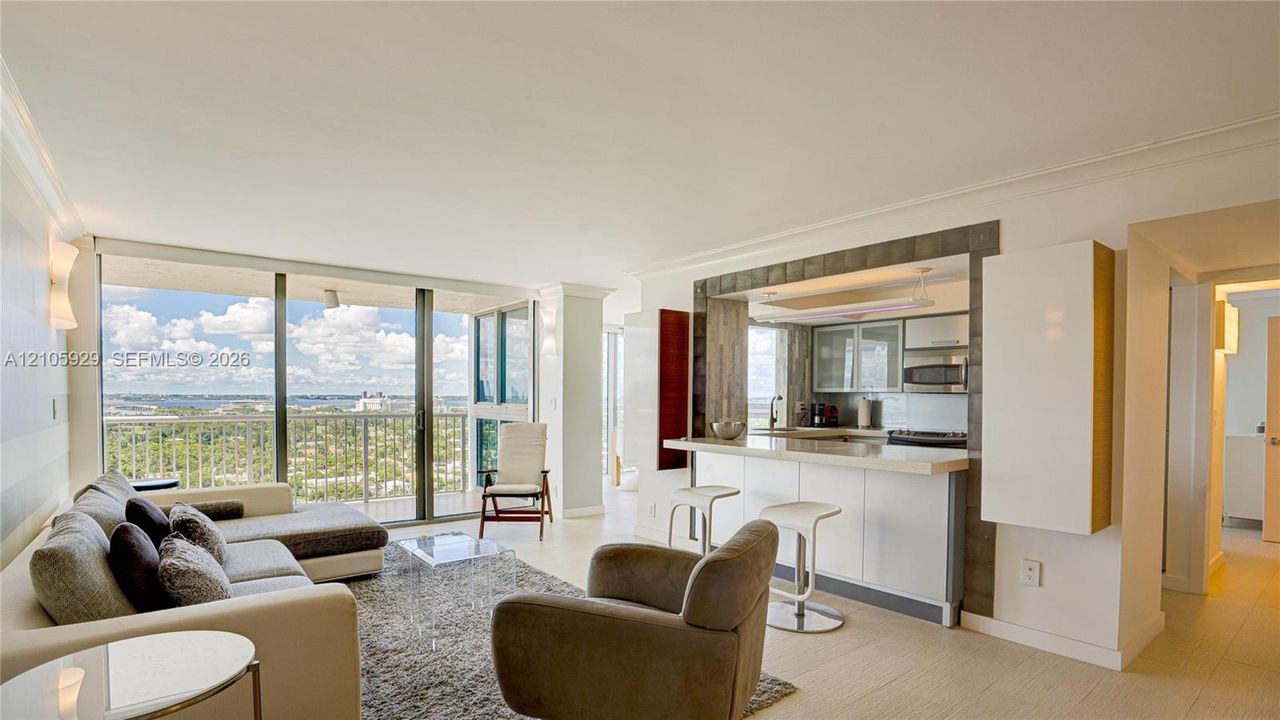 Floor-to-ceiling glass doors, open-concept kitchen with breakfast bar, built-in cabinetry, tile flooring, and expansive balcony