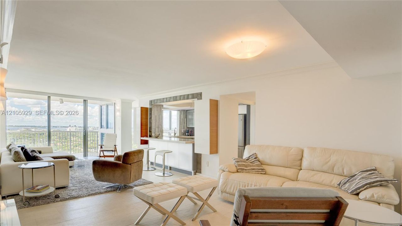 Open-concept interior featuring light-toned flooring, floor-to-ceiling glass sliding doors, and a kitchen area with a built-in counter