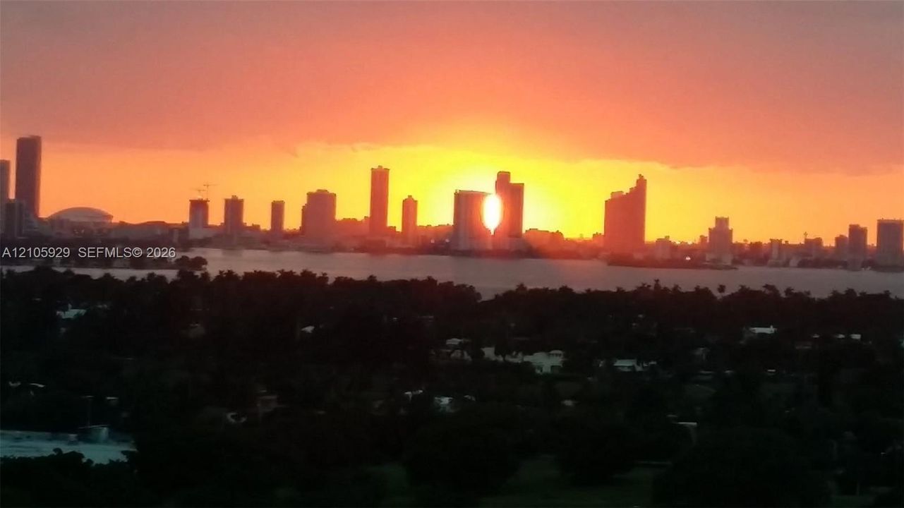 Panoramic skyline of metropolitan high-rises, coastal waterfront, and sunset backdrop
