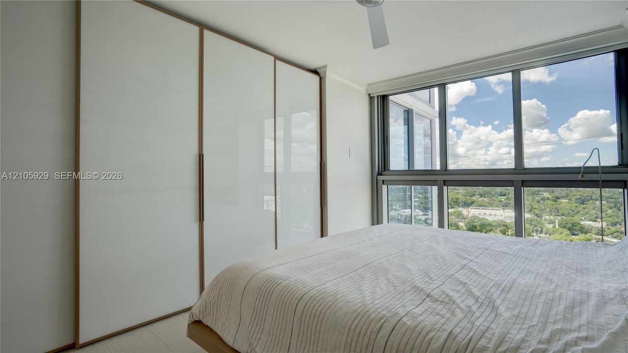 Floor-to-ceiling windows, built-in floor-to-ceiling closets with white panels and trim, and a ceiling fan