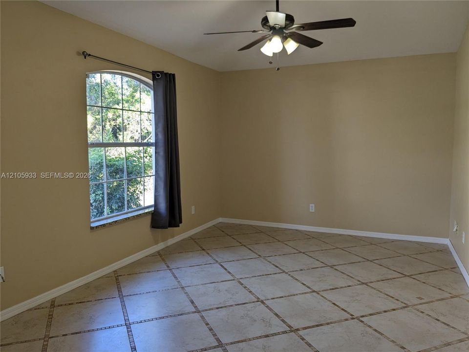 Interior space featuring diamond-patterned tile flooring, an arched window, and a multi-light ceiling fan