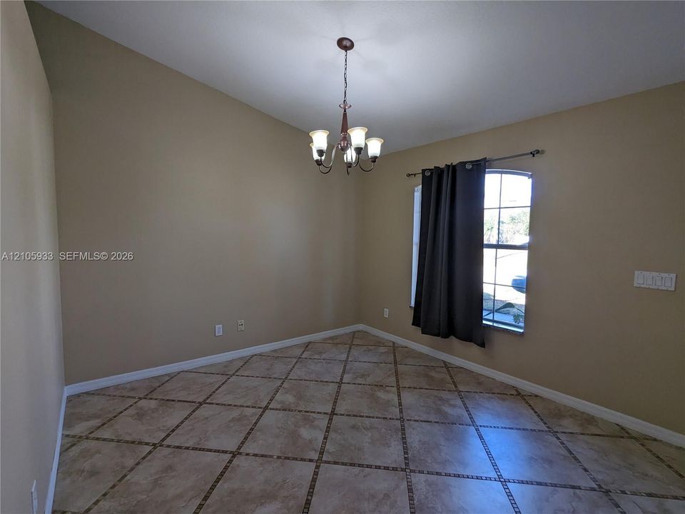 Vaulted ceiling, arched window, and large-format tile flooring with decorative inlay