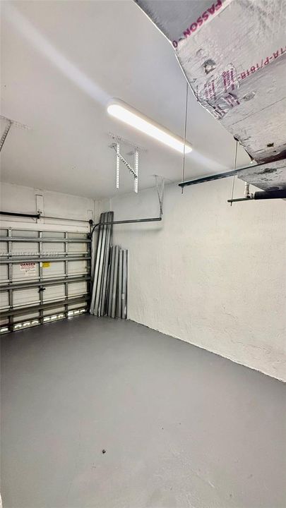 Attached garage featuring a metal sectional door, painted concrete flooring, and linear LED ceiling lighting