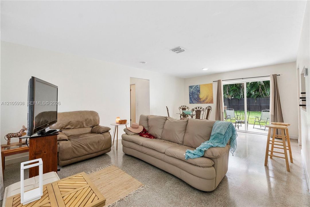 Polished concrete flooring, recessed lighting, and sliding glass doors providing outdoor access
