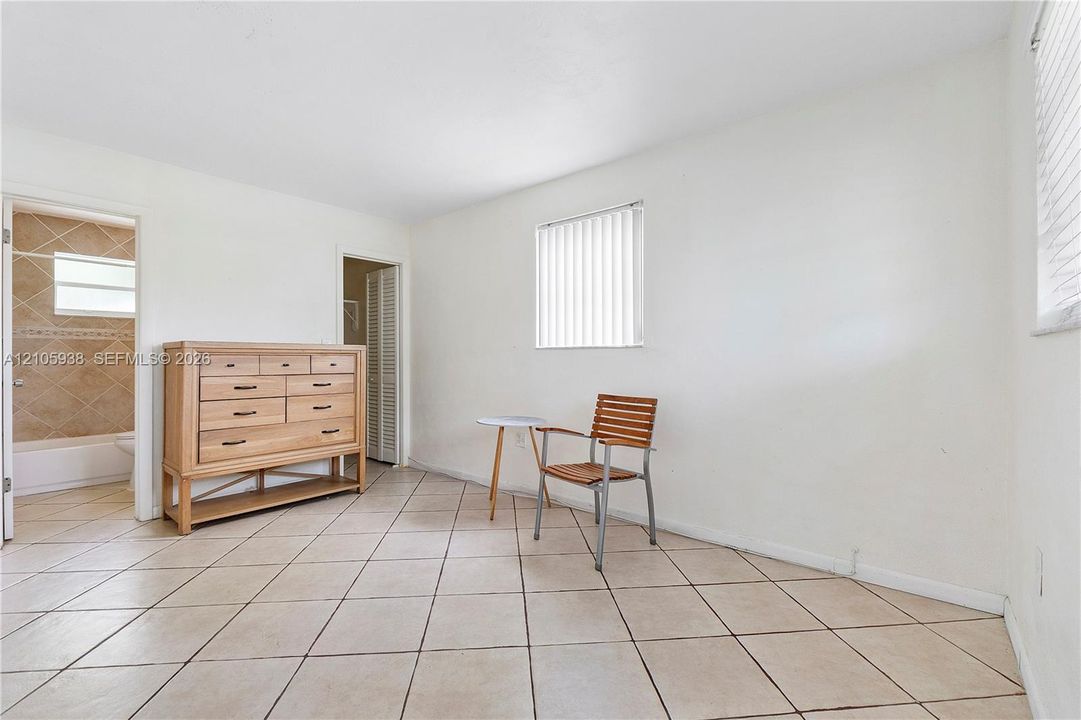 Neutral-toned ceramic tile flooring, vertical window blinds, and louvered closet doors