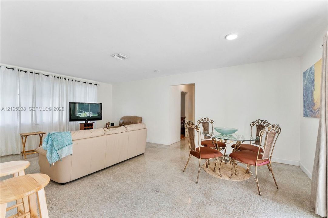 Open-concept interior featuring light-toned flooring, expansive windows with drapery, and recessed lighting