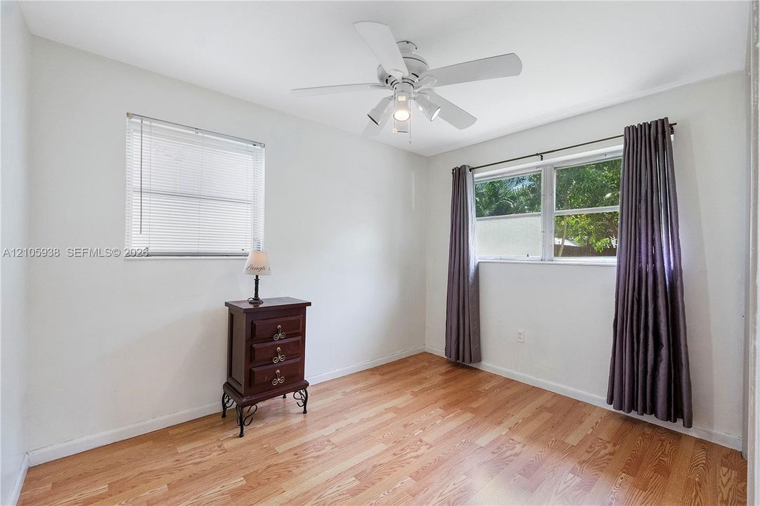 Interior space featuring wood-finish flooring, a neutral color palette, dual-pane windows, and a multi-light ceiling fan