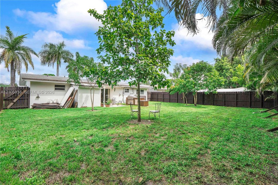 Expansive backyard featuring a fenced perimeter, mature trees, and open green space
