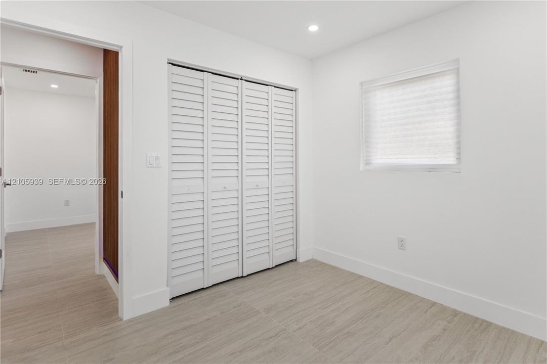 Room featuring wood-finish flooring, white walls, louvered bi-fold closet doors, and recessed lighting