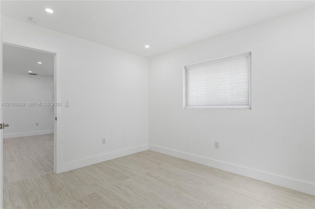 Neutral interior featuring wood-finish flooring, recessed lighting, and a window with a pleated shade