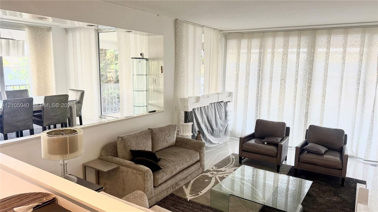 Large-scale wall mirror, neutral tile flooring, and floor-to-ceiling sliding glass panels