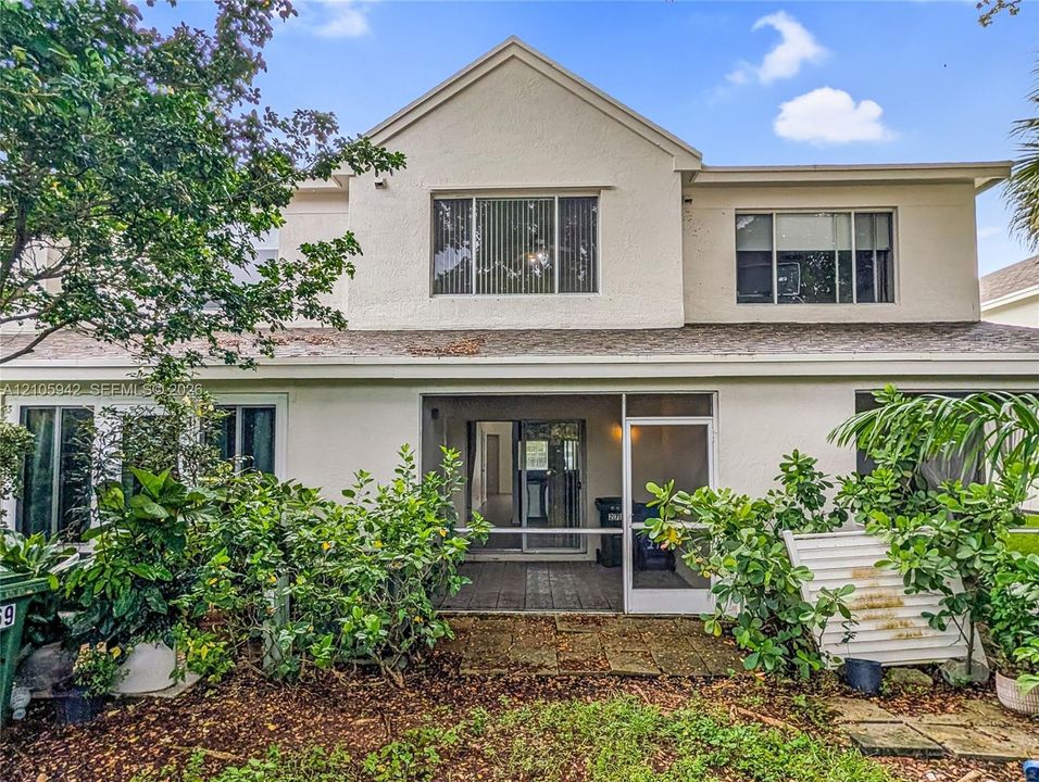 Rear exterior featuring a covered patio, stucco siding, multi-level design, and private chain-link fencing