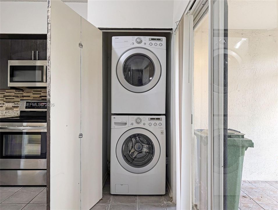 Stacked washer and dryer unit, stainless steel microwave, stainless steel range, and tile flooring