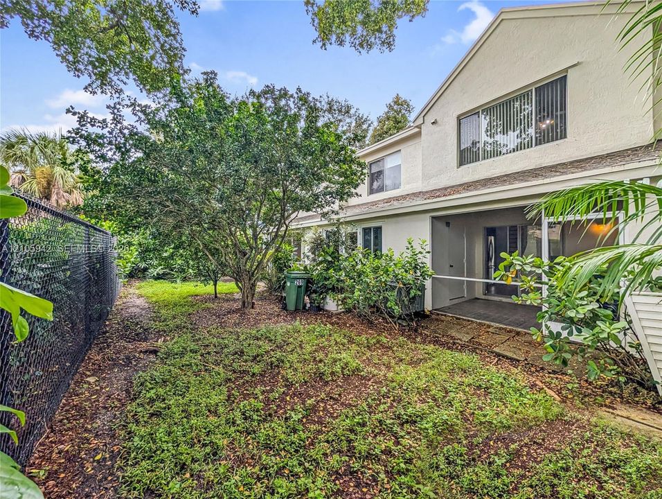 Rear exterior featuring a covered patio, stucco siding, multi-level design, and private chain-link fencing