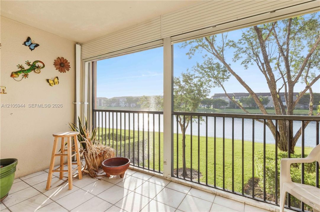 Screened-in balcony featuring tile flooring, metal railings, and direct water frontage
