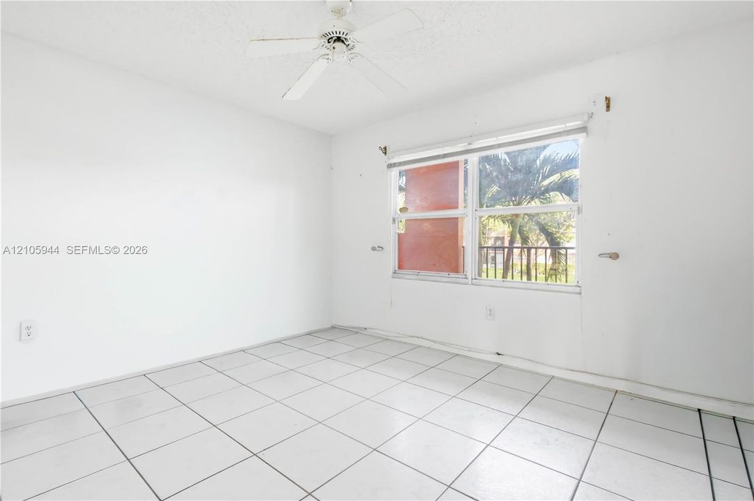 White-tiled flooring, ceiling fan with light fixture, and dual-pane window with white blinds