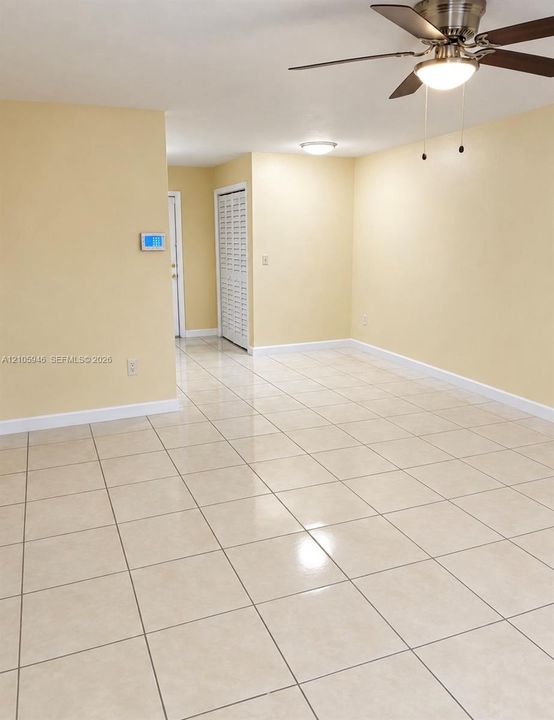 Neutral-toned ceramic tile flooring, ceiling fan with integrated lighting, recessed flush-mount light fixture, and closet with louvered doors