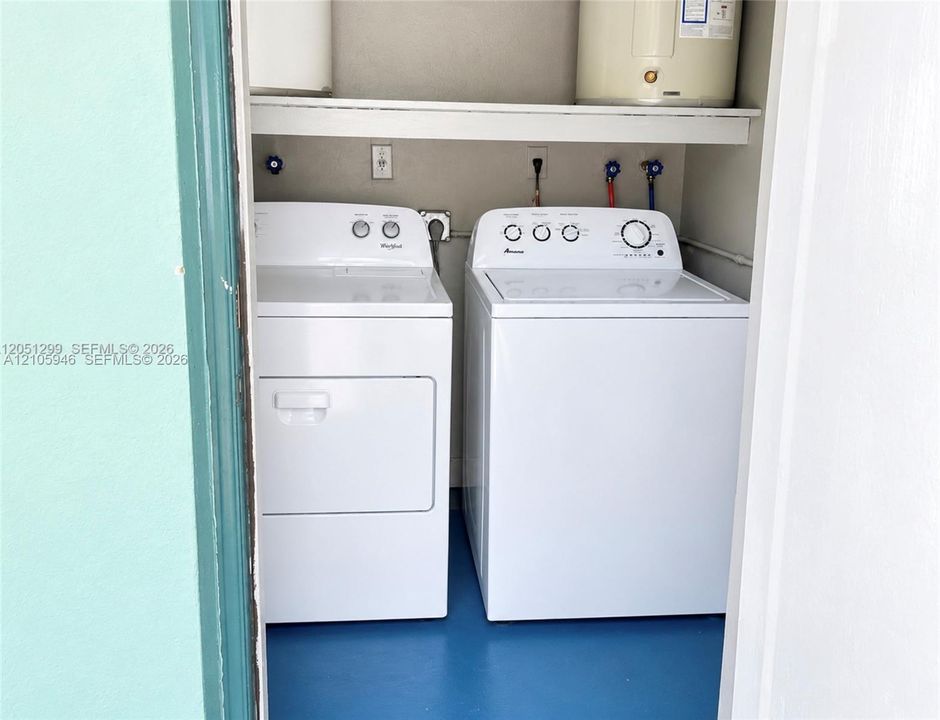 Laundry closet featuring built-in shelving, hard-surface flooring, and utility connections