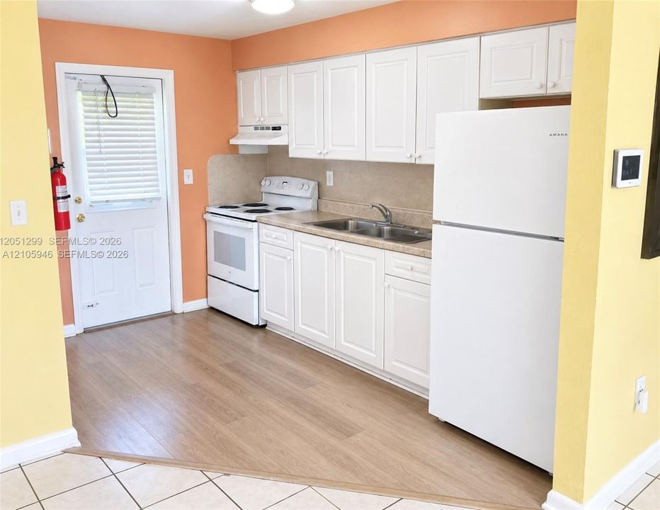 Kitchen featuring white cabinetry, wood-finish flooring, a stainless steel dual-basin sink, and a built-in appliance suite