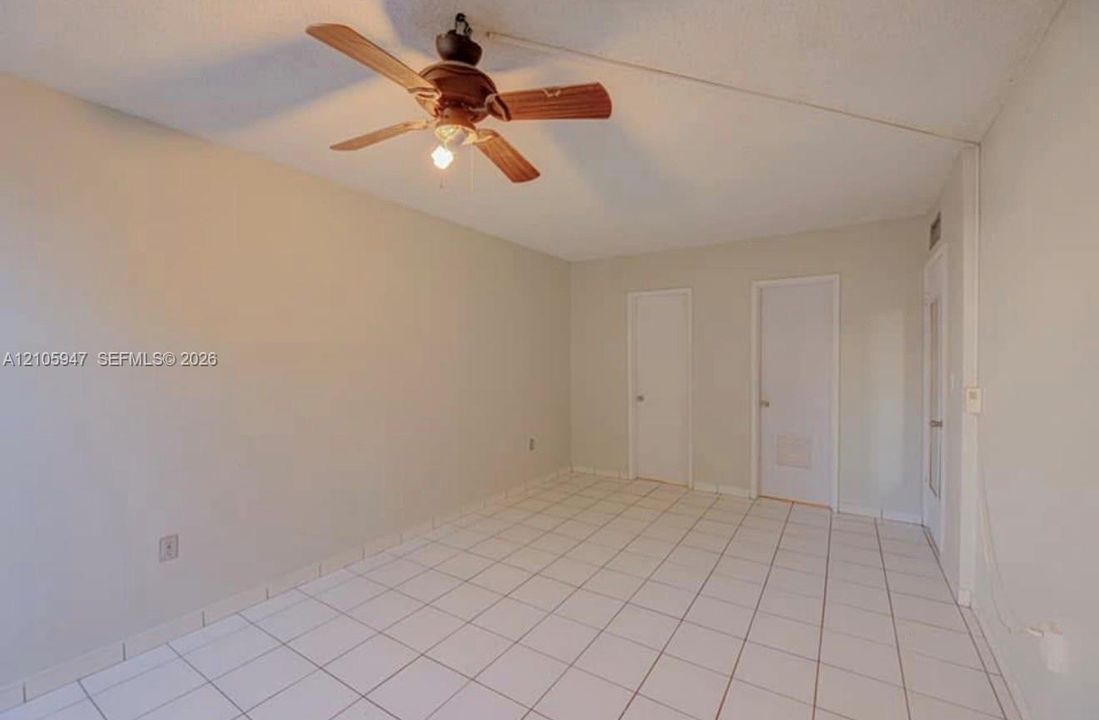 Interior space featuring square ceramic tile flooring, neutral wall tones, and a ceiling-mounted light fixture with a multi-blade fan