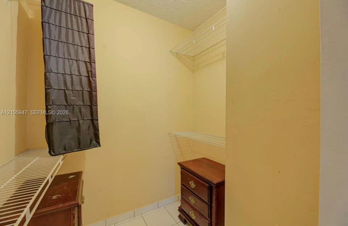 Walk-in storage space featuring white wire shelving and tile flooring