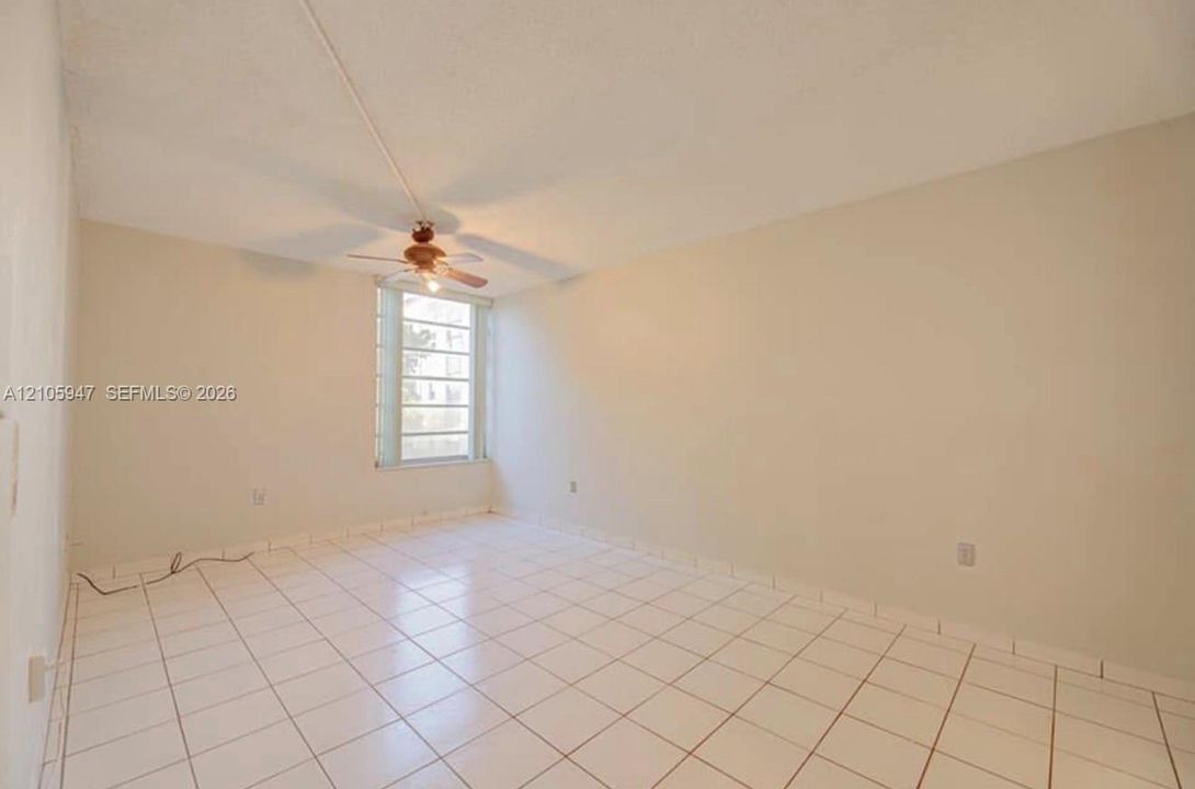 Interior space featuring tile flooring, neutral wall paint, a multi-pane window, and a ceiling fan with integrated lighting