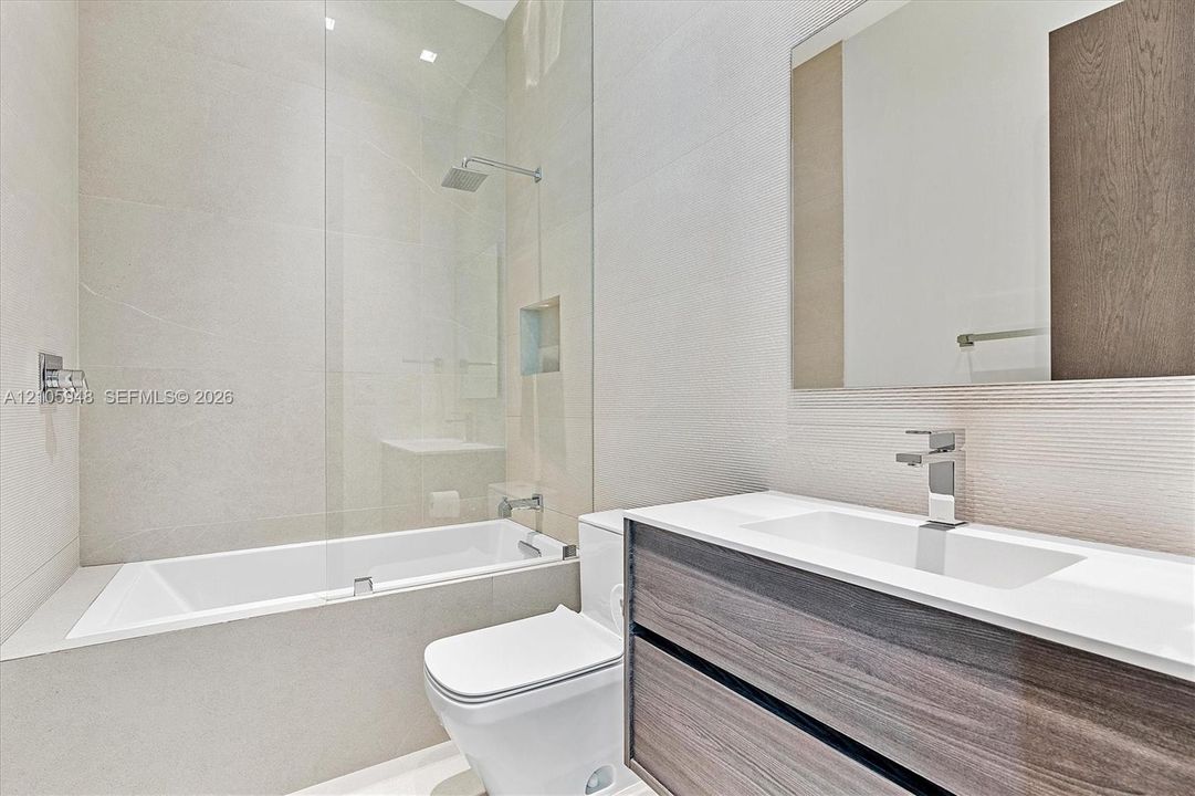 Floating dual-drawer vanity with white countertop, undermount sink, rainfall shower system, glass panel enclosure, and wall-mounted mirror