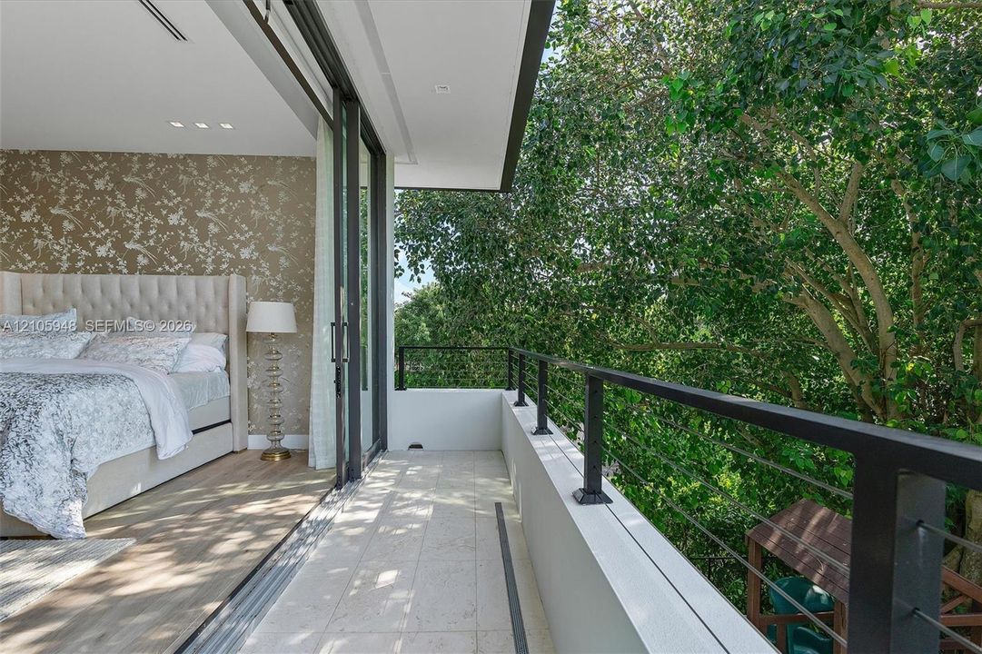 Private balcony with stone flooring, metal railings, recessed lighting, and large-format sliding glass doors
