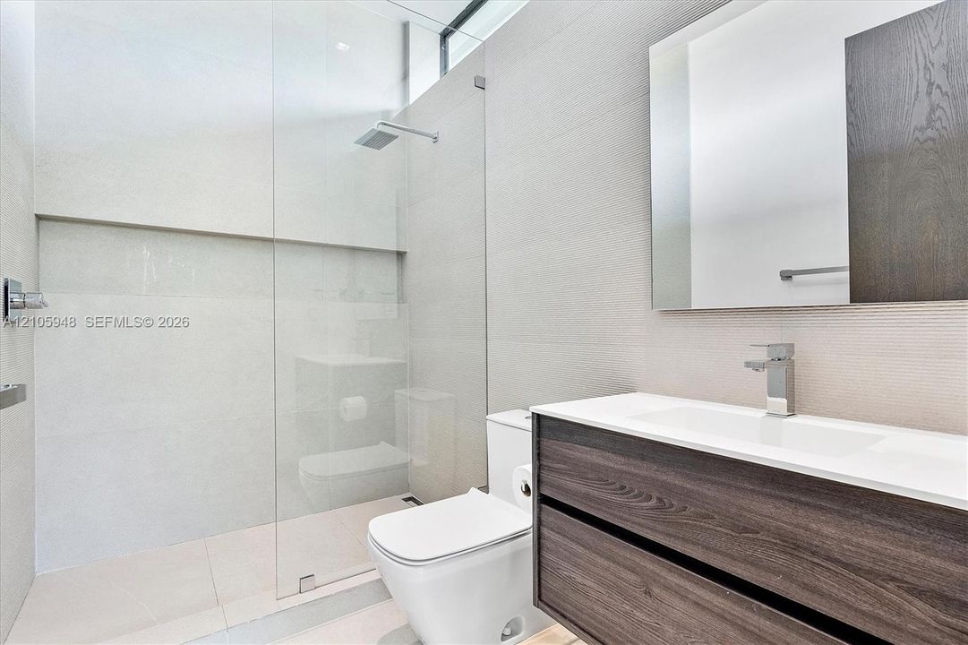 Modern floating vanity featuring wood-finish cabinetry, white countertop, integrated sink, and rectangular wall mirror