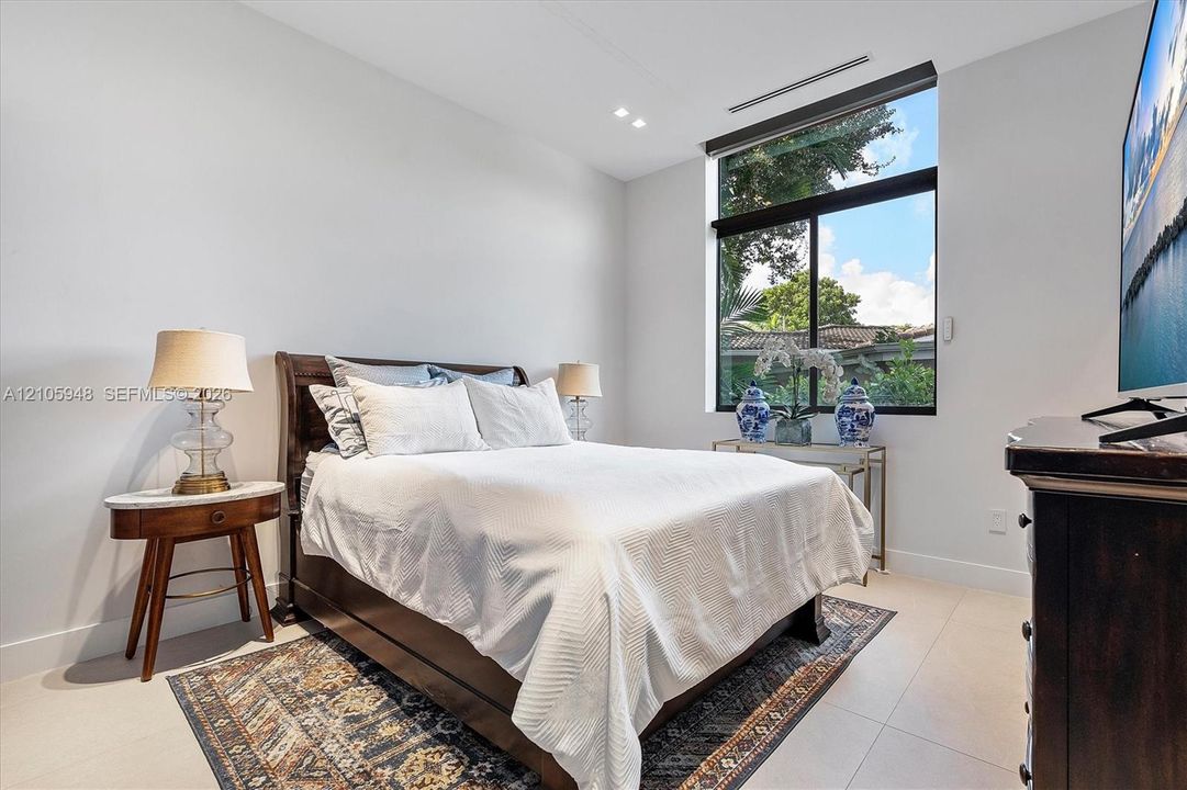 Neutral-toned room featuring large-format tile flooring, recessed ceiling lighting, and an oversized window with black trim