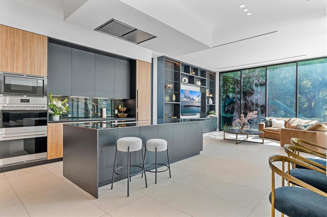Custom kitchen featuring dual-tone cabinetry, a large center island, floor-to-ceiling glass sliding doors, and built-in shelving