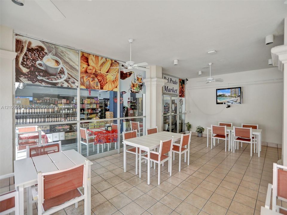 Covered patio featuring large-format floor tiling, multiple ceiling-mounted fans, and full-height glass storefront windows