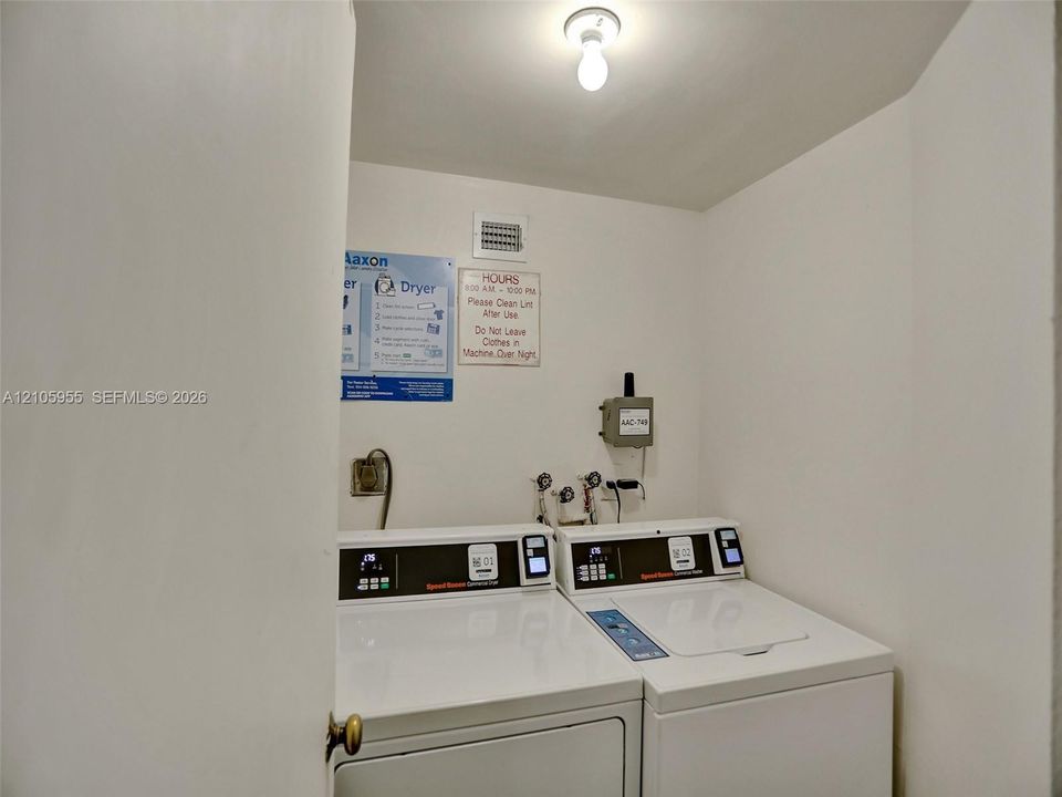 Utility area featuring built-in commercial-grade laundry appliances, wall-mounted water hookups, and surface-mounted ceiling lighting