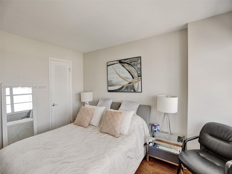 Neutral wall color, wood-finish flooring, and single-panel door with louvred upper detail
