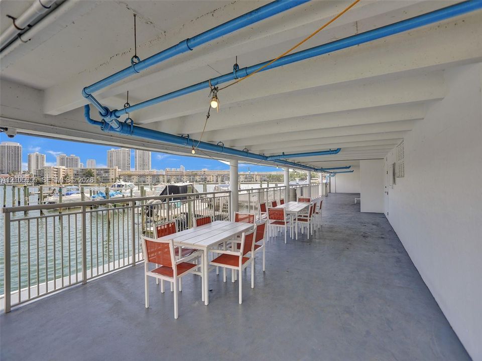 Covered outdoor terrace featuring a concrete floor, metal railings, and direct water access