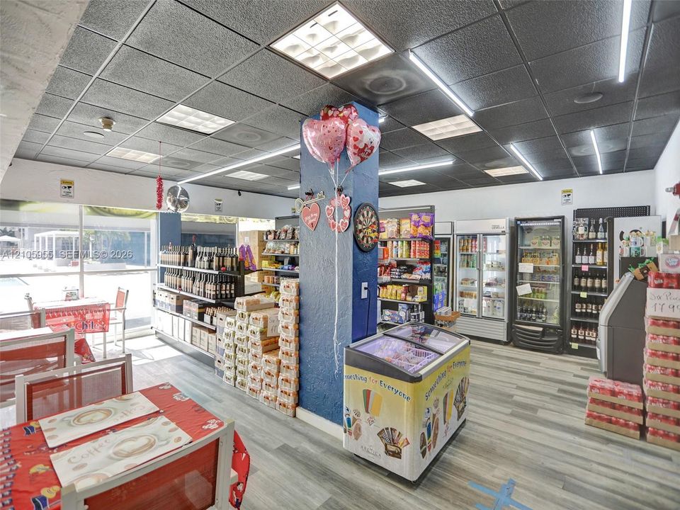 Commercial interior featuring wood-finish flooring, grid-panel drop ceiling, recessed linear lighting, and floor-to-ceiling glass wall panels