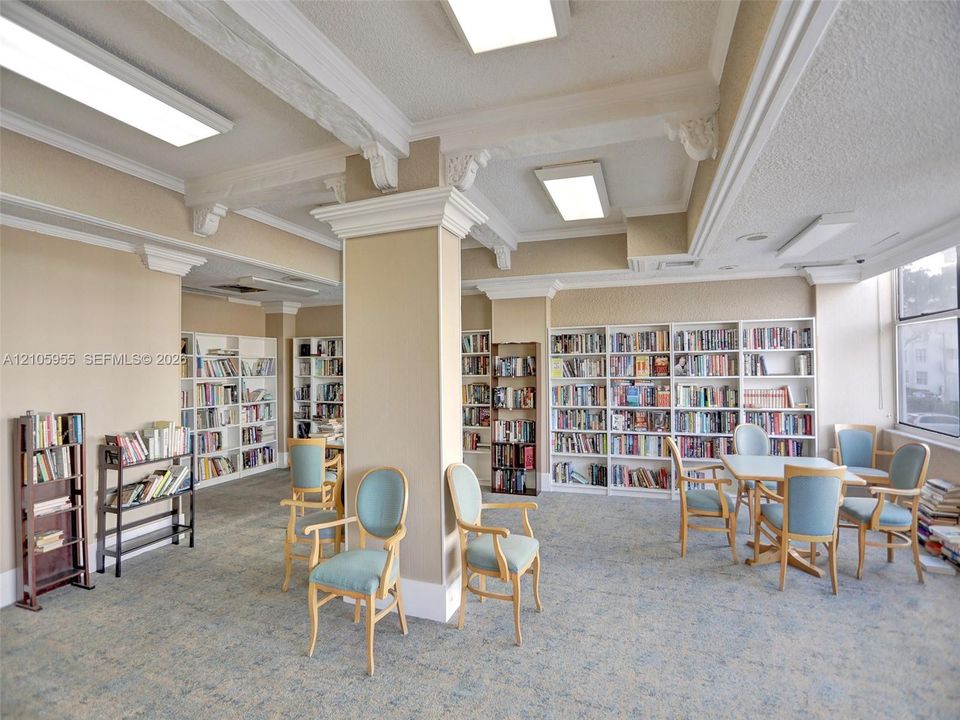 Built-in floor-to-ceiling shelving, decorative ceiling beams with crown molding, and large window placement providing natural light