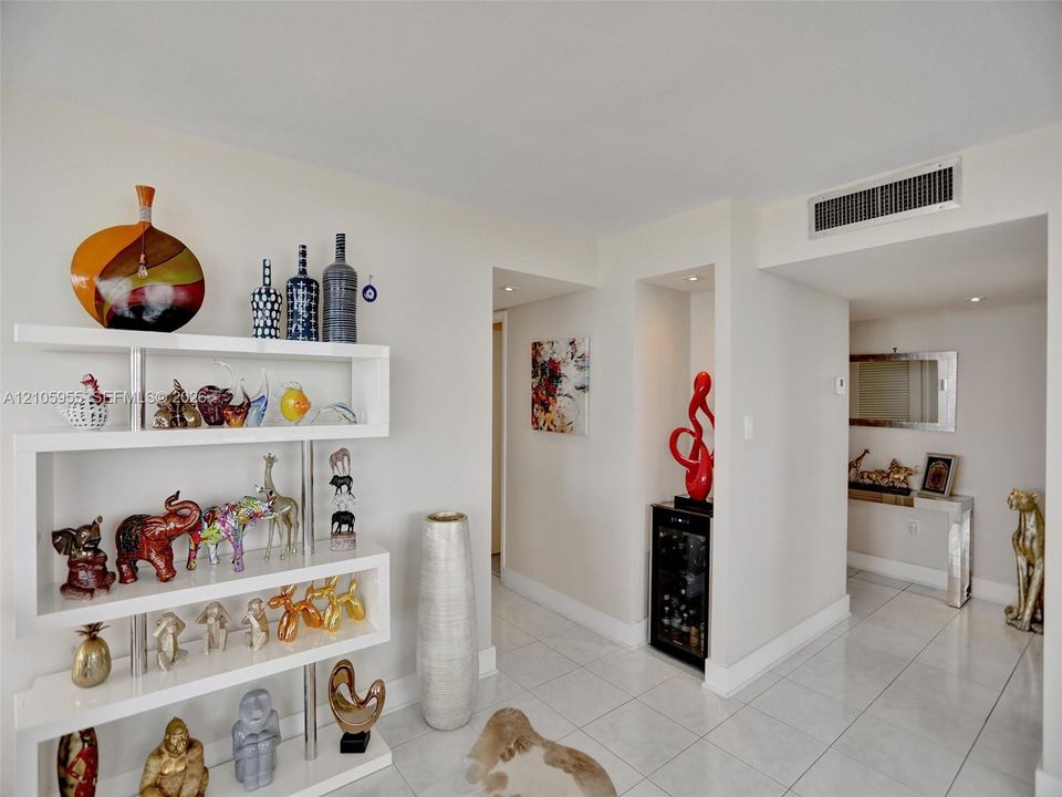 Glossy tile flooring, custom white built-in display shelving, and a recessed beverage refrigerator
