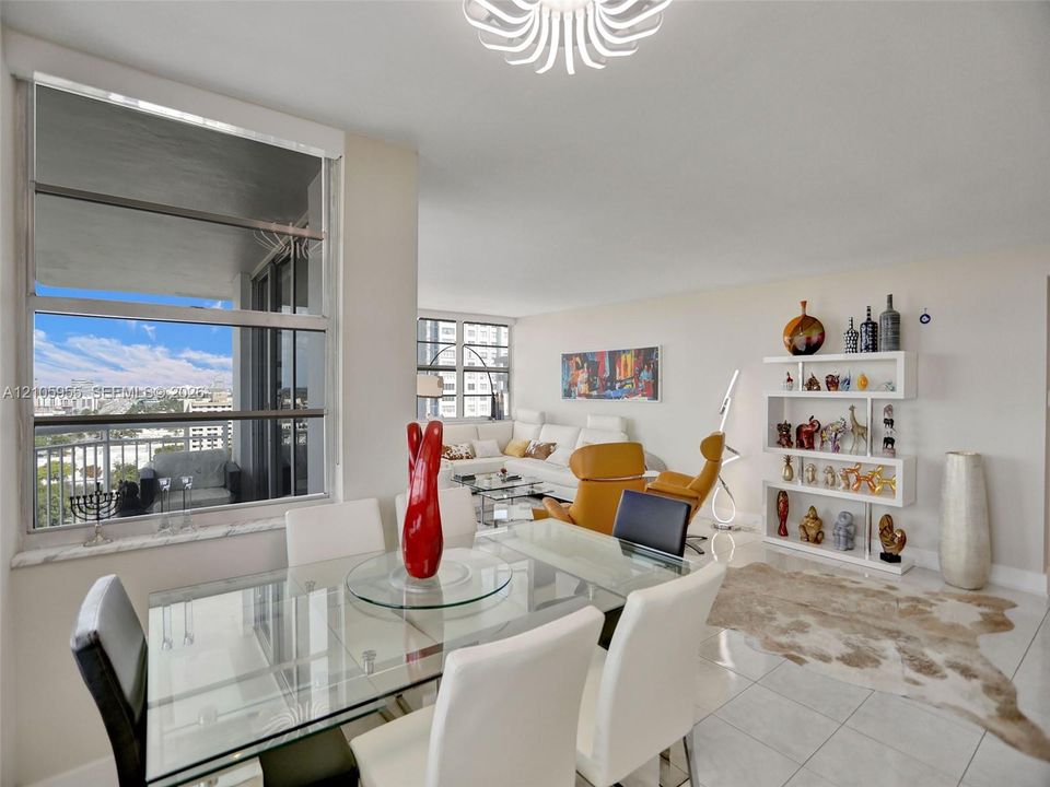 Open-concept living space featuring large-format tile flooring, expansive floor-to-ceiling windows, built-in shelving unit, and decorative ceiling fixture