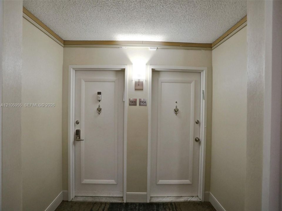 Solid-core entry doors featuring brushed nickel hardware, door knockers, and wall-mounted sconce lighting