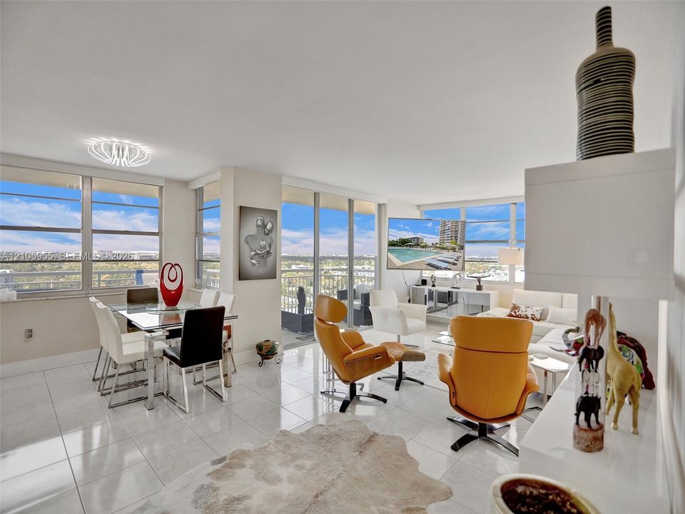 Open-concept interior featuring large-format ceramic tile flooring, floor-to-ceiling windows, a private balcony, and contemporary overhead lighting