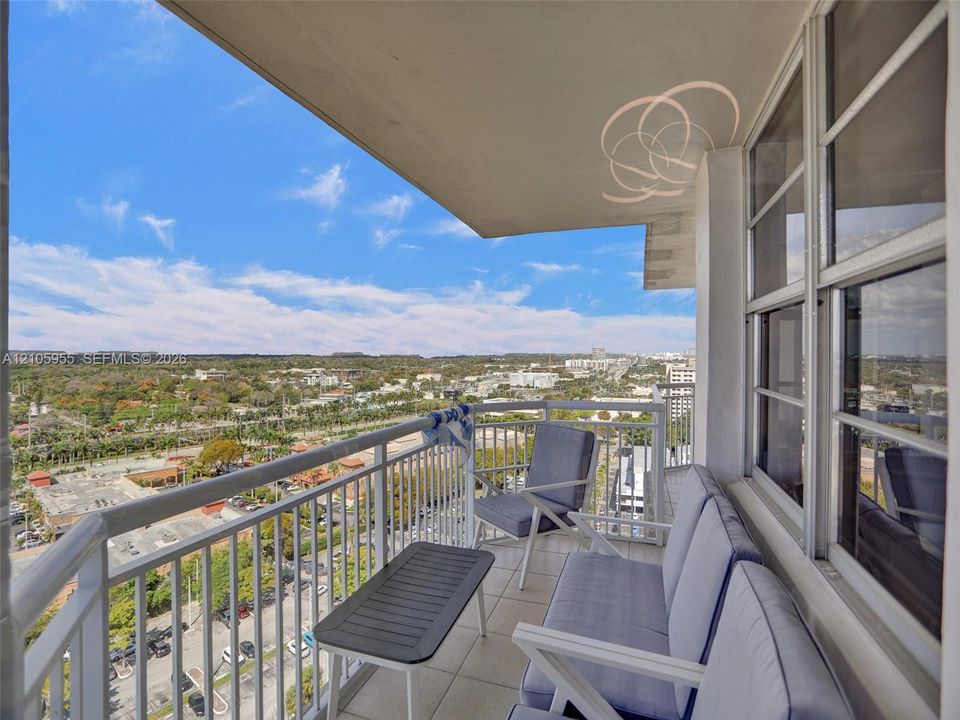 Covered balcony featuring white metal railings and tile flooring