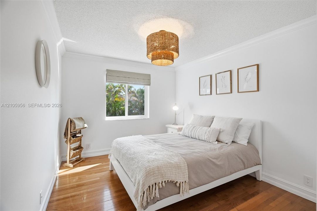 Room featuring wood-finish flooring, crown molding, and a drum-style ceiling light fixture